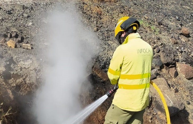 El incendio forestal de Mijas queda completamente extinguido tras varias horas de trabajo - bombero e1780338560945 Imagen de archivo de un bombero del INFOCA refresca una raíz humeando en la zona del incendio.
